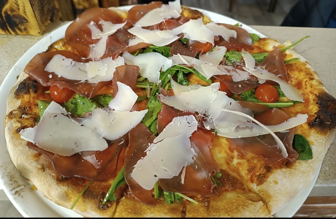 Primavera pizza with Prosciutto di Parma, arugula, cherry tomatoes and shaved Parmesan